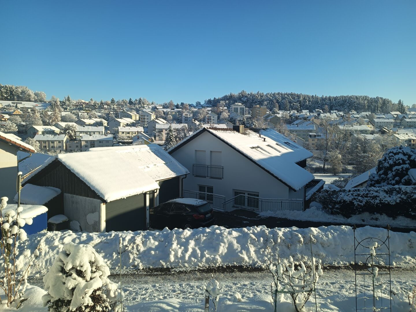 DE: Blick aus dem Fenster über Schneebedeckte Winterdächer und dem Wald am Horizont vor dem blauen klaren Himmel.
EN: View from the window over snow-covered winter roofs and the forest on the horizon against the blue clear sky.